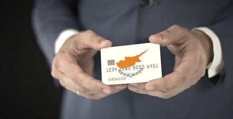 Businessman holds plastic bank card with printed flag of Cyprus, fictional numbers