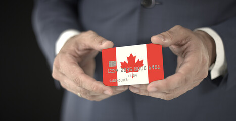 Businessman holding plastic bank card with printed flag of Canada, fictional numbers