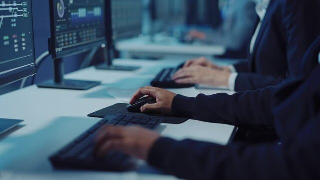 Close Up Hands Footage of a Technical Support Specialist of Software Engineer Working on a Computer in a Dark Monitoring and Control Room. He types on Keyboard and Moves the Mouse.