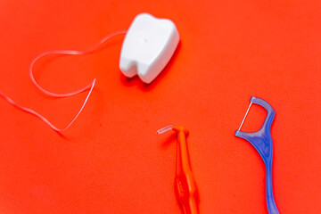 Different types of dental floss and tooth picks on red background. Dental floss in tooth toy shape.
