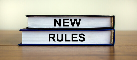 Books with text 'new rules' on wooden table. Beautiful white background. Business concept, copy space.