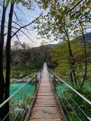 Bridge over river Soca in Soca valley Kobarid Slovenia. Orange. blue and green colors. Pedestrian bridge made out of wood. Picture was taken on 13th of October 2019.