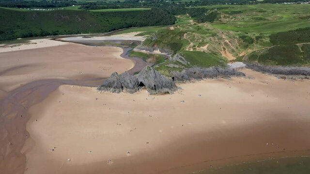 Aerial drone view flying along a huge sandy beach in a beautiful setting (3 Cliffs Bay and Pobbles, Gower Peninsula, Wales)