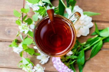 A cup of tea. Transparent glass cup of tea, top view. Against the background of flowers. Summer, natural healthy food.