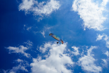 Paragliders soar on beautiful paragliders against the background of blue sky and blue sea, shot from the top of the mountains