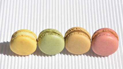 Assortment of four different flavored macarons ordered in a row on a striped wavy white background