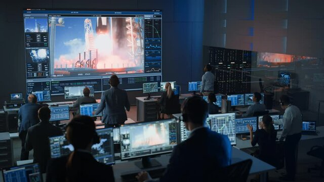 Group of People in Mission Control Center Witness Successful Space Rocket Launch. Flight Control Employees Sit in Front Computer Displays and Monitor the Crewed Mission. Team Stand Up and Clap Hands.
