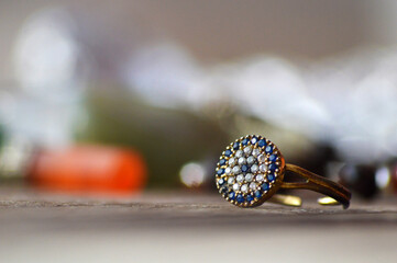 Old gold color ring and open with blue and white stones on a table and blur background