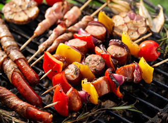 Grilled various food, sausages and vegetable and meat skewers with herbs on a cast iron grill close up view