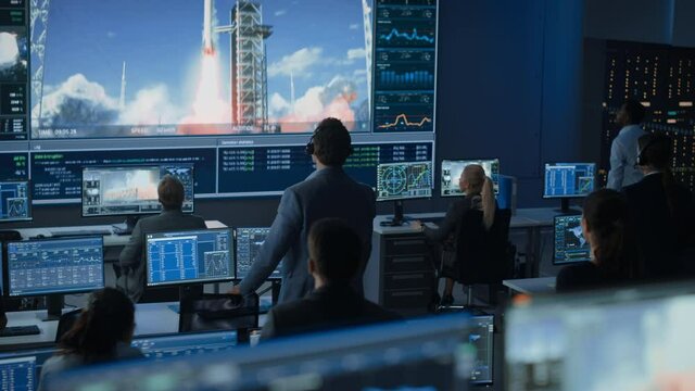 Group of People in Mission Control Center Witness Successful Space Rocket Launch. Flight Control Employees Sit in Front Computer Displays and Monitor the Crewed Mission. Team Stand Up and Clap Hands.