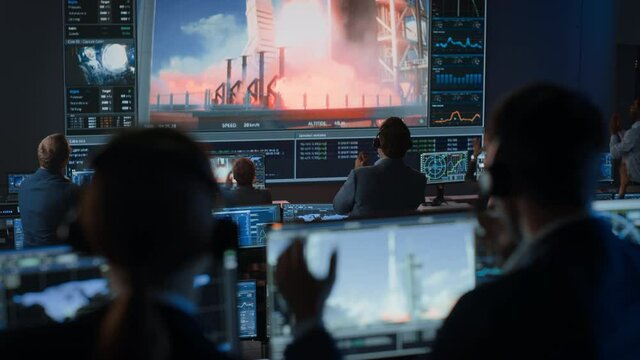 Group of People in Mission Control Center Witness Successful Space Rocket Launch. Flight Control Employees Sit in Front Computer Displays and Monitor the Crewed Mission. Team Stand Up and Clap Hands.