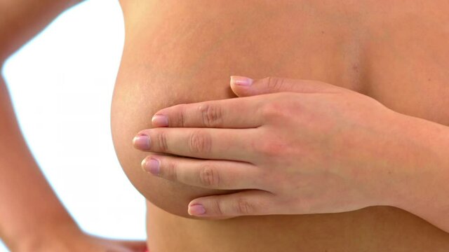 Woman with large breast doing breast examination and looking for signs of breast cancer.