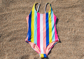 multicolored swimsuit lies on the sand on the beach