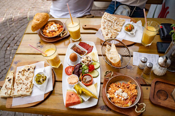 High angle view of various food and drink served on wooden table at sidewalk cafe