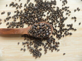 Brown color raw whole Buckwheat grains or Fagopyrum esculentum on wooden spoon