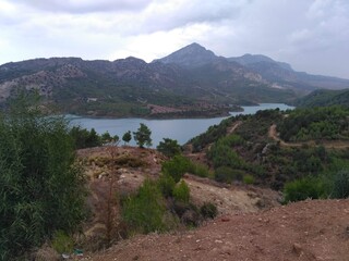 Blue lake in the mountains, overcast sky. There are brown grass and picturesque paths on the rocks.