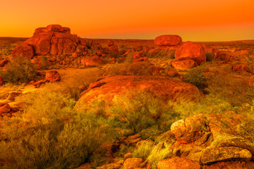 Vibrant orange and red colors of sunset sky over giant granite boulders at Karlu Karlu or Devils Marbles in Northern Territory, Australia.
