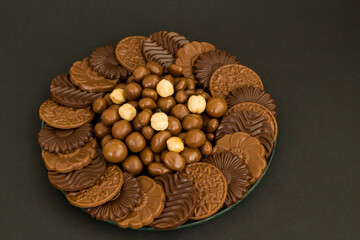 Milky and bitter round shape chocolate Madlen,designed on glass plate,at black background with copy space.Top view