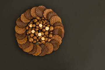 Milky and bitter round shape chocolate Madlen,designed on glass plate,at black background with copy space.Top view