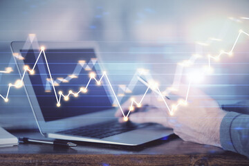 Double exposure of man's hands holding and using a digital device and forex graph drawing. Financial market concept.