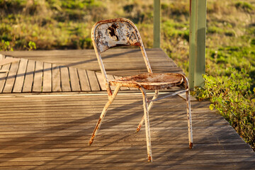 Rusty old antique metal chair on wooden porch of country house