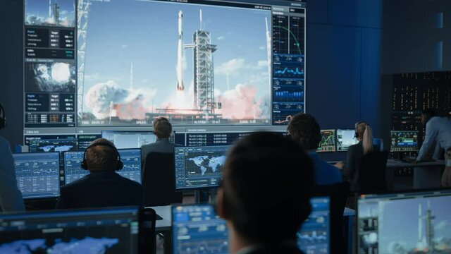 Group of People in Mission Control Center Witness Successful Space Rocket Launch. Flight Control Employees Sit in Front Computer Displays and Monitor the Crewed Mission. Team Stand Up and Clap Hands.