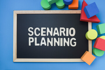 Block letters on scenario planning on the black chalkboard and colorful blocks on blue background