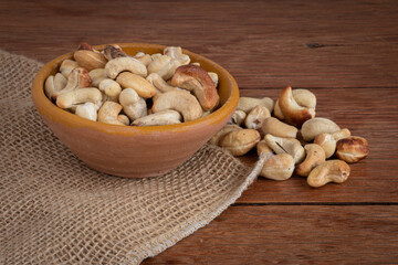 Tasty cashew nuts in bowl on wooden table. Space for text