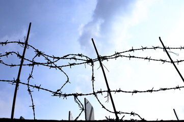 Rusty barbed wire fence with shards of glass prevents climbing