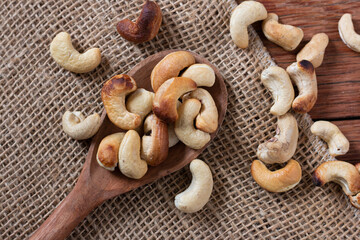 Tasty cashew nuts in wooden spoon on wooden table. Space for text. Top view.