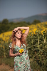 Beautiful young woman in a field of sunflowers in a green dress