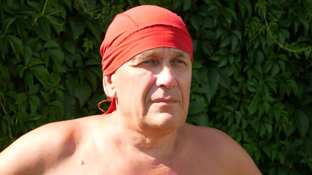 A portrait of an old sailor with a red bandana looking into the distance