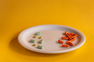 White plate with colored medications on a orange background. Pharmaceutical drug overdose concept.