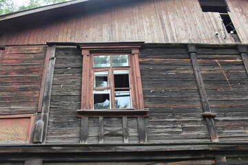 broken glass shards in the window of an old ruined wooden house