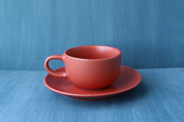 Red clay Cup and saucer on a gray background. Empty ceramic Cup. Selective focus. Tableware. A couple of tea