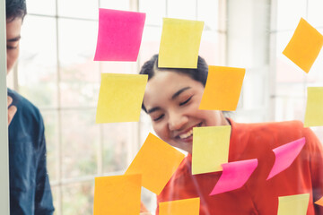 Business people work on project planning board in office and having conversation with coworker...