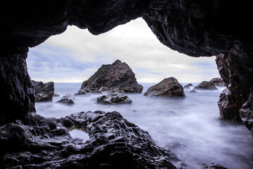 Curious and beautiful of the aeches in the rock cave in the early morning,long exposure sea wave.	