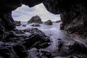 Curious and beautiful of the aeches in the rock cave in the early morning,long exposure sea wave.	