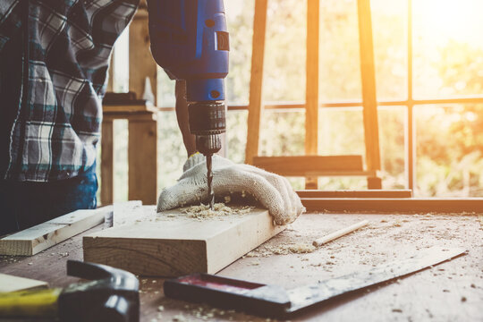 Carpenter working on wood craft at workshop to produce construction material or wooden furniture. The young Asian carpenter use professional tools for crafting. DIY maker and carpentry work concept.