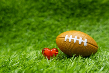 American football with love heart shape on green grass