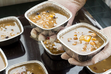 Gloved hand is serving dessert ashura with black ladle,close up