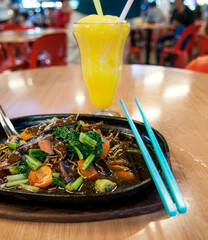 Plate of cooked vegetables and mushrooms with slushy ice drink in night market held in 