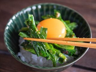 温かいご飯の上に乗せた卵黄とニラのピリ辛和えのクローズアップ。