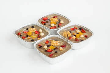 Traditional Turkish Dessert is Noah's Pudding,Asure in foil containers ,take away package,on the white surface with copy space.