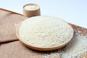 White sesame seeds isolated on a white wooden background