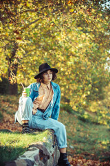 Enjoying. Autumn model. Bright make up. Woman on background fall landscape leaves of trees.