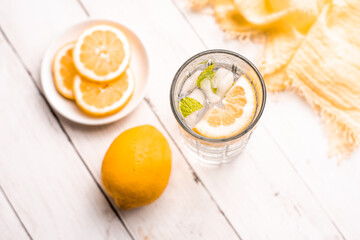 Cold Detox Water with lemon slices and mint on a white wood table 