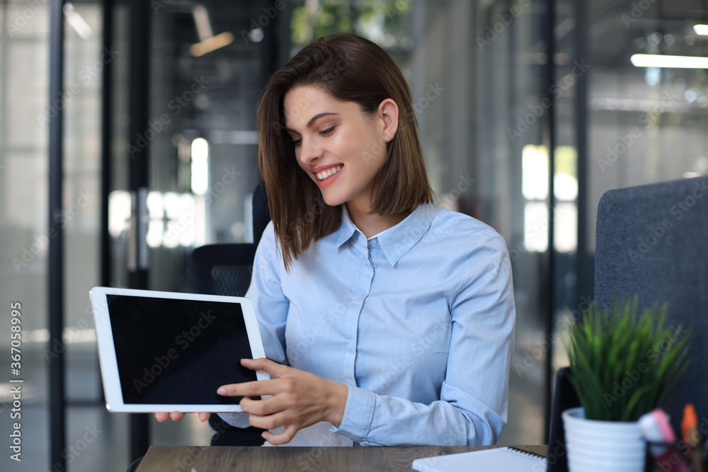 Wall mural young happy business woman showing blank tablet computer screen in office.