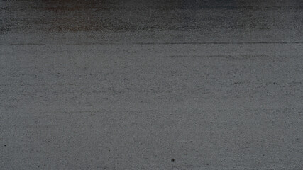 Asphalt road surface wet with rain drops. Oblique view from the side.