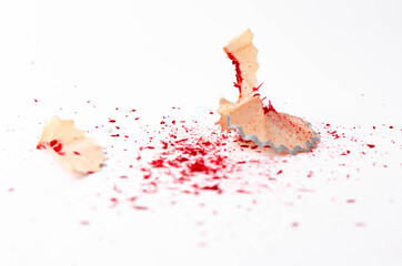 Shavings of red pencil in close-up on a white background. Pencil lead whole and broken on a white background. Leftovers from a pencil. Macro, a pile of shavings